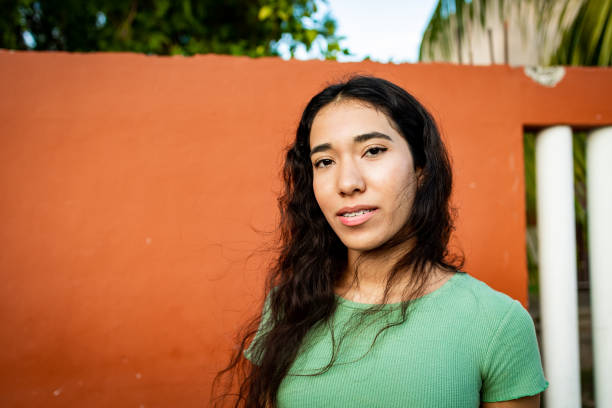 A teen in a green shirt against an orange wall